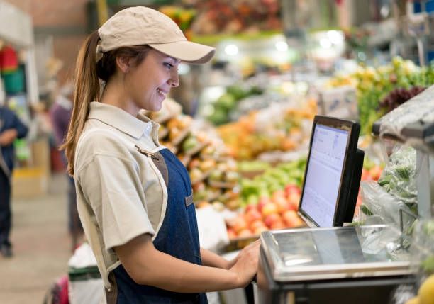 Young Latin American cashier working at a supermarket using the___